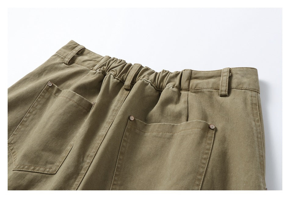 Close-up of khaki trousers with an elasticated waistband, belt loops and large patch pockets.