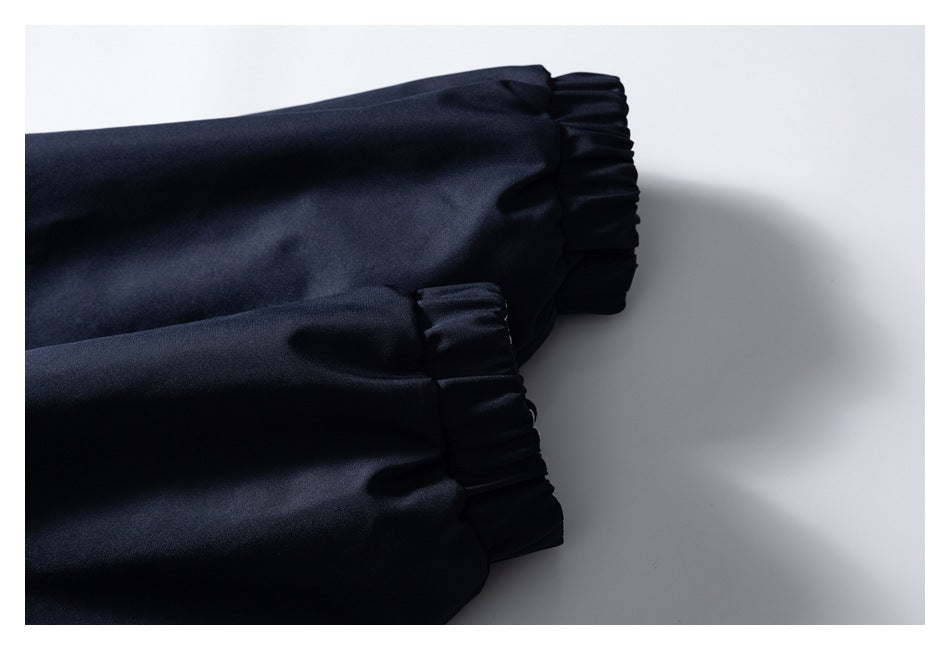 Close-up of two dark navy jacket sleeves showing their gathered cuffs.