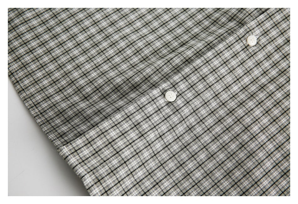 Close-up of the gray plaid shirt fabric and two white buttons.