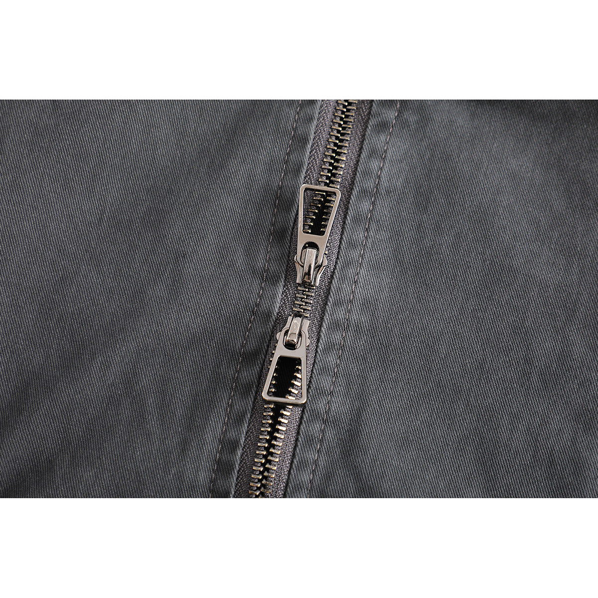 Close-up of the charcoal jacket's metal front zipper and two decorative zipper pulls.