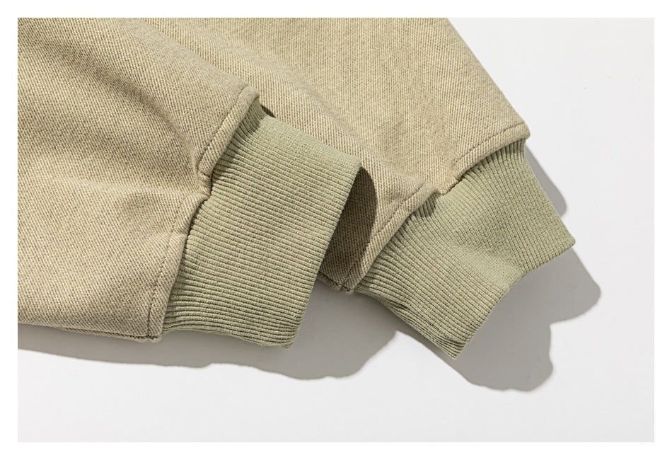 Close-up of two sage ribbed cuffs attached to a light beige garment.