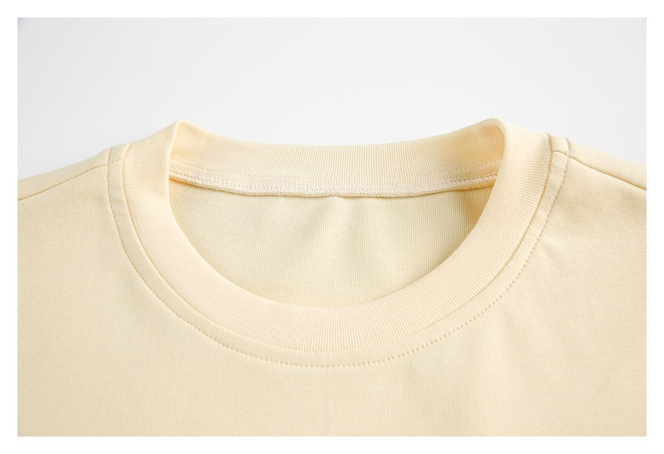 Close-up of the cream garment's ribbed crew neckline and shoulder seams.