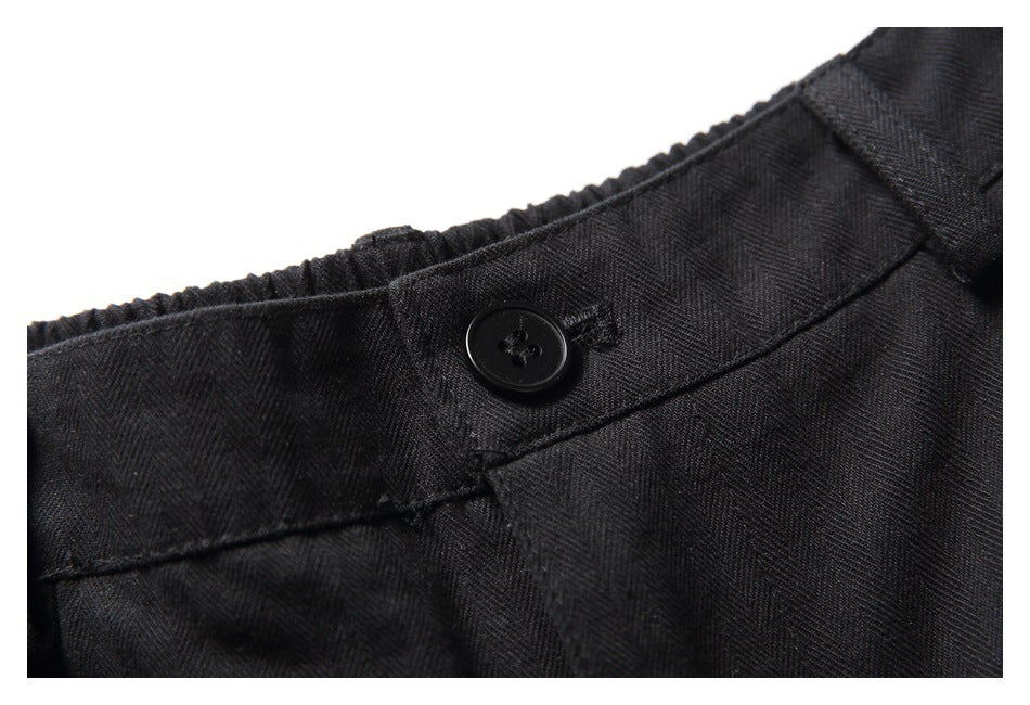 Close-up of a black button and stitched waistband on black shorts.