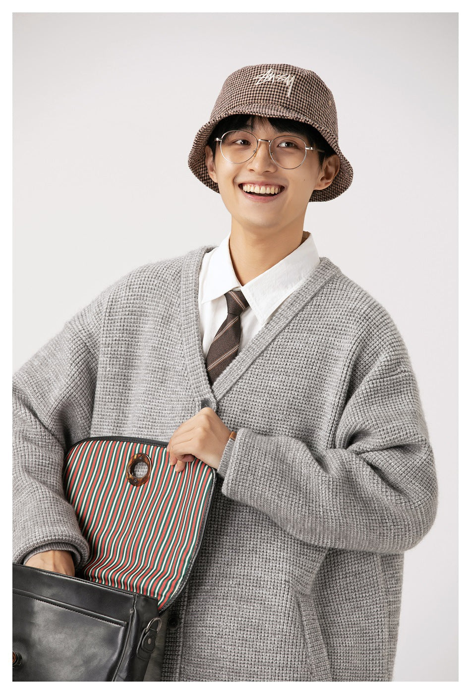Close view of a model wearing a gray textured cardigan over a white shirt and striped tie.