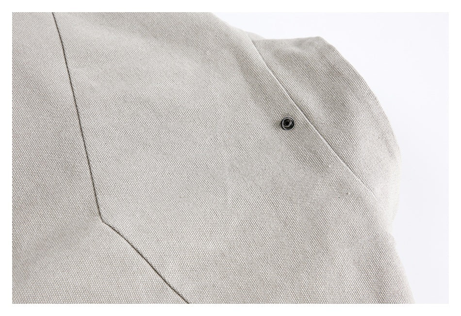 Close-up of the taupe woven jacket fabric, seam, and a small dark snap.