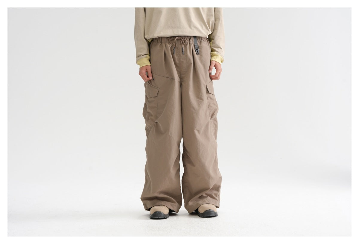 Front view of a model wearing loose taupe cargo pants with a drawstring waist and large side pockets.