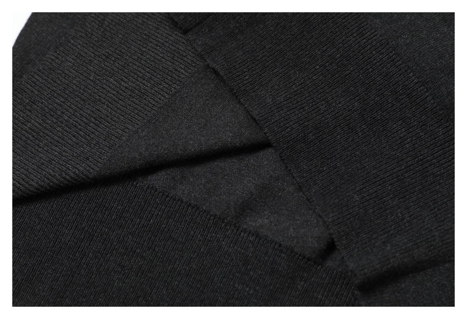 Close-up of black ribbed knit fabric with overlapping garment seams.