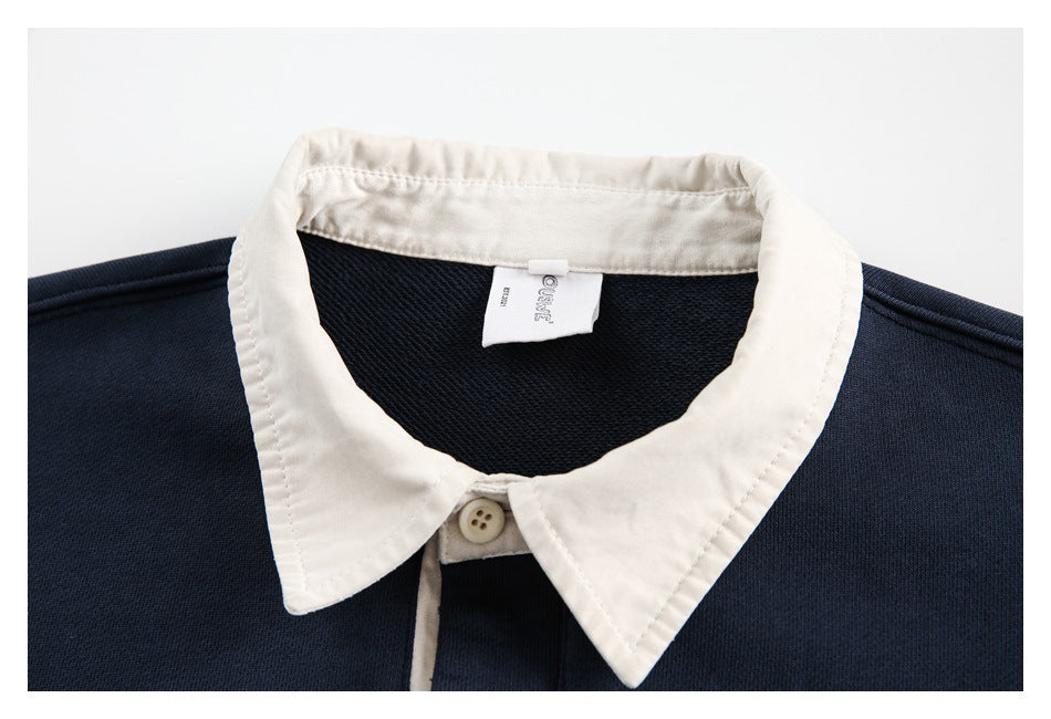 Close-up of the sweatshirt's cream pointed collar, top button, and inner neck label against navy fabric.