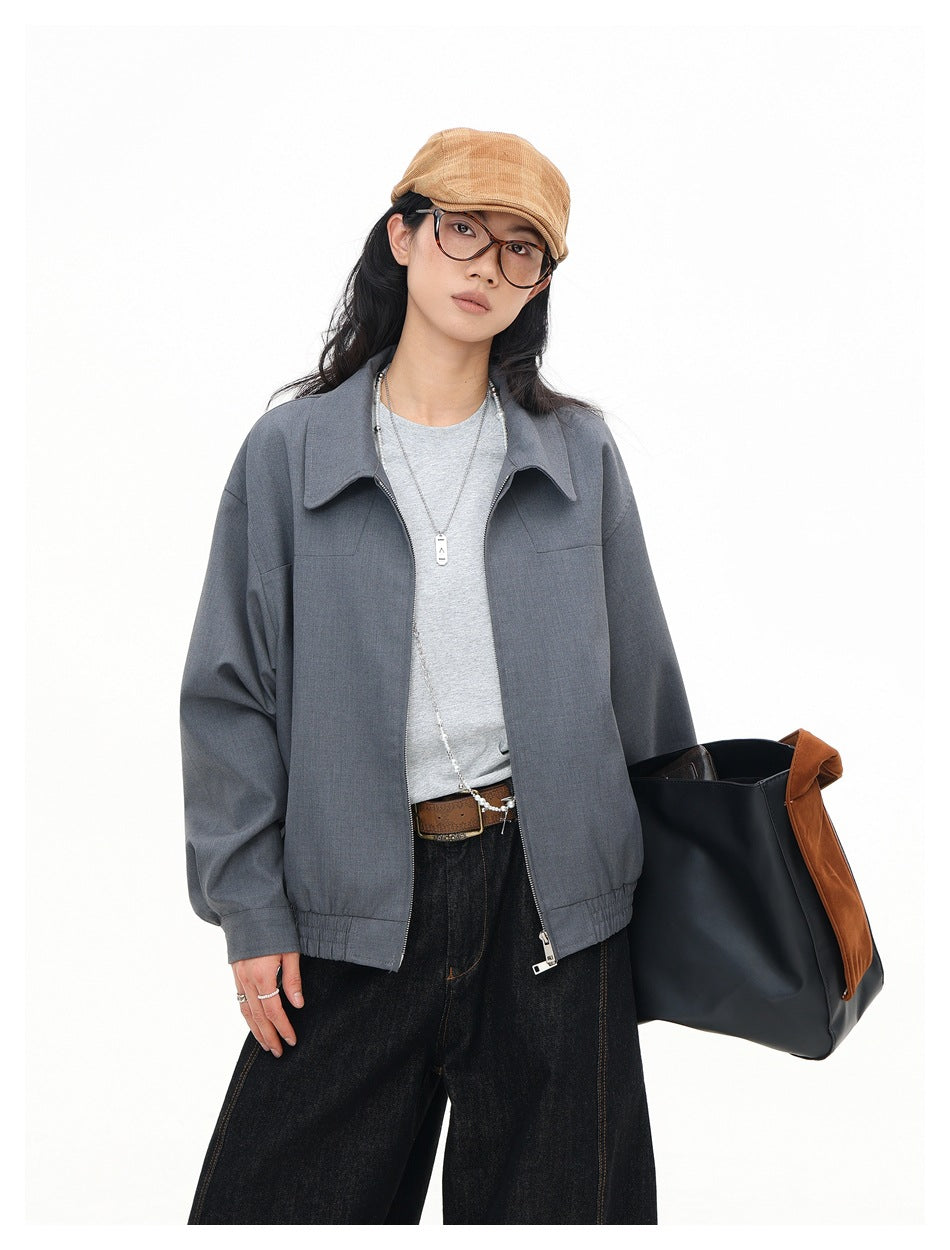 Closer front view of a model wearing an open gray zip-front jacket with a pointed collar.