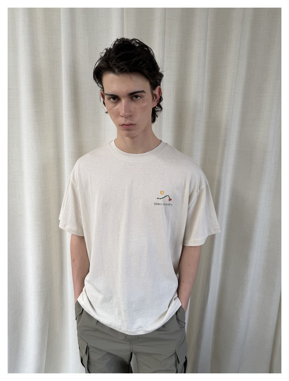Close view of a model wearing a white T-shirt with a small multicolor chest graphic.