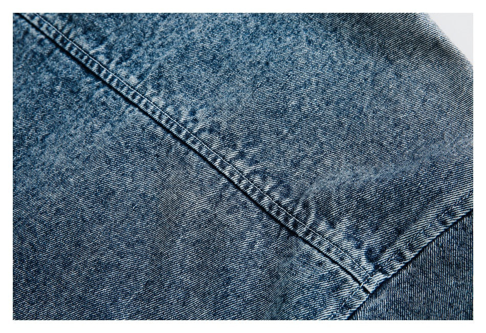 Close-up of blue denim showing diagonal stitched seams and a faded finish.