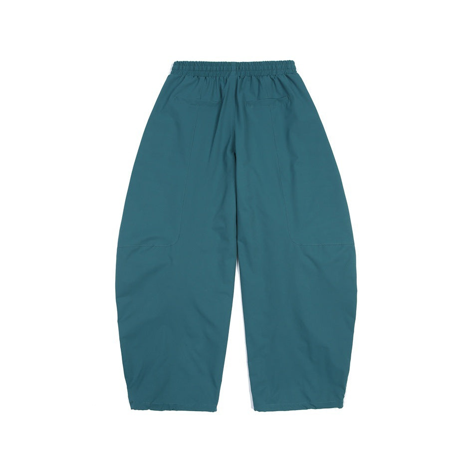 Back view of teal loose-fit pants with an elastic waistband and large patch pockets.