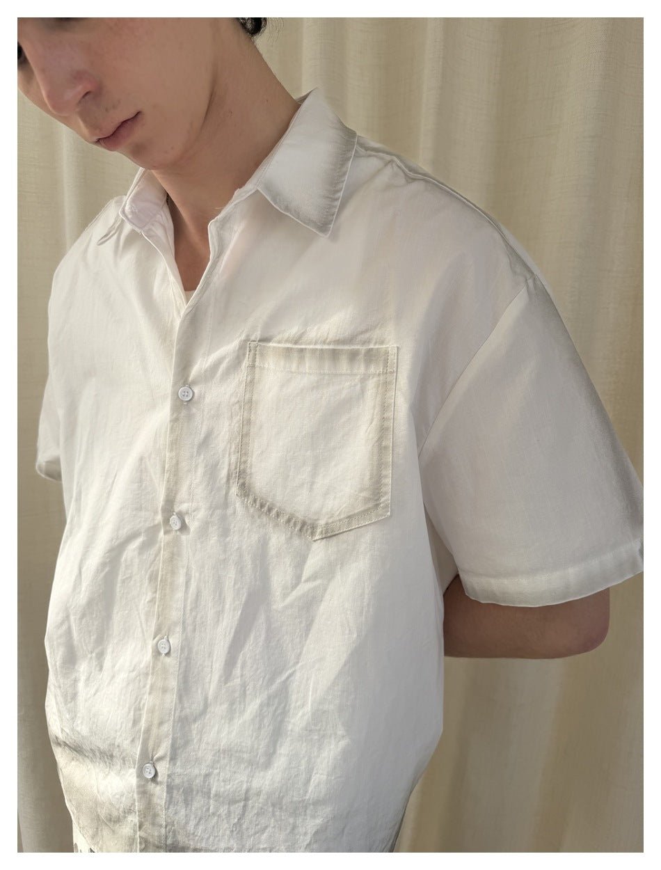 Close view of the white shirt’s pointed collar, front buttons, and single chest pocket.