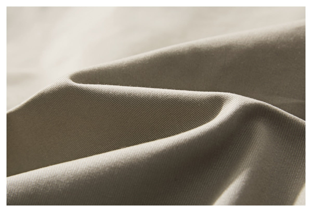 Close-up of beige jacket fabric draped in folds, showing its fine diagonal weave.