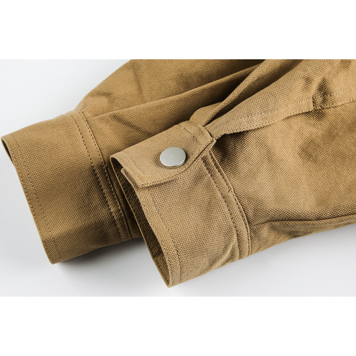 Close-up of a tan jacket sleeve cuff with a silver snap tab and visible stitching.