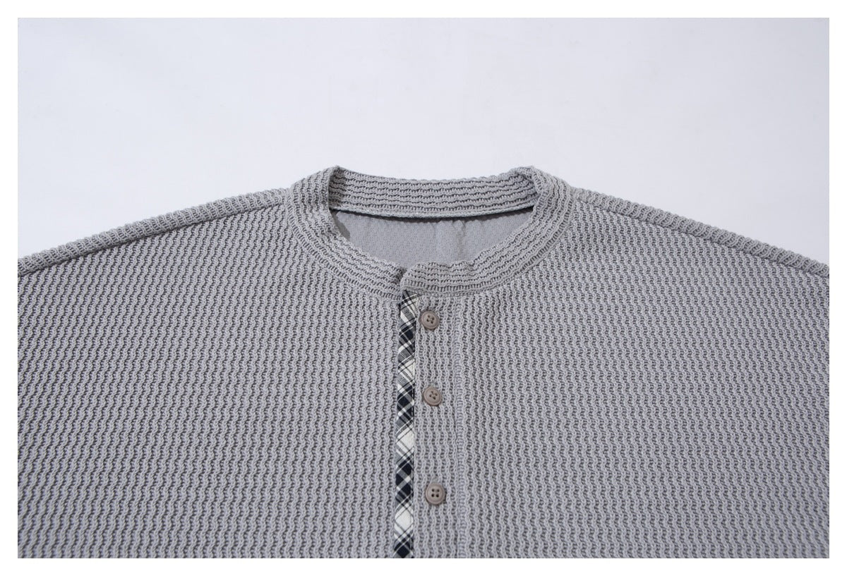 Close-up of a light gray textured knit cardigan front with a round neckline and button placket.