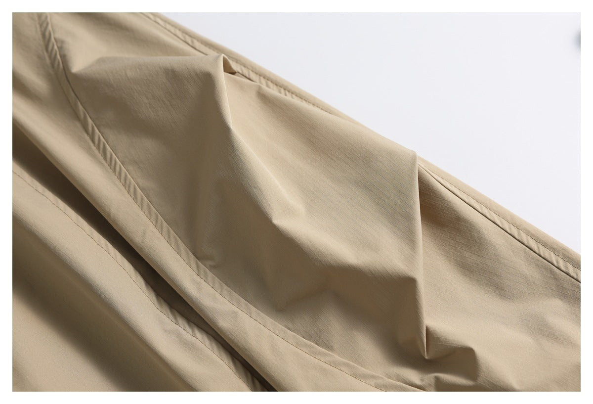 Close-up of tan garment fabric folded to show a stitched seam and panel construction.