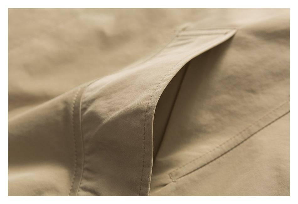 Close-up of a beige garment showing a folded edge, stitched seams, and a small buttonhole.