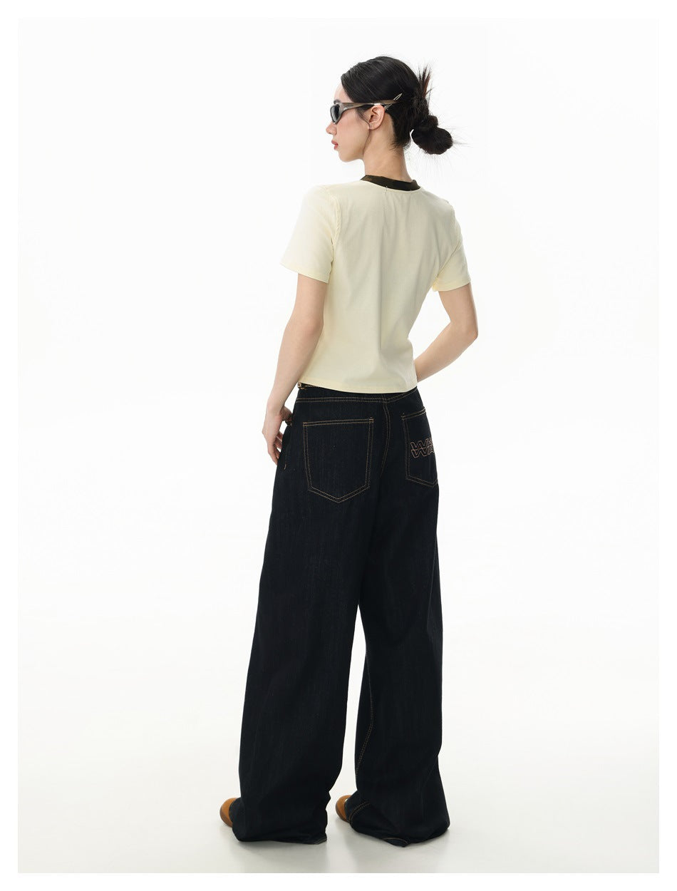 Full-length rear view of a model wearing an ivory T-shirt and dark wide-leg jeans with back pockets.