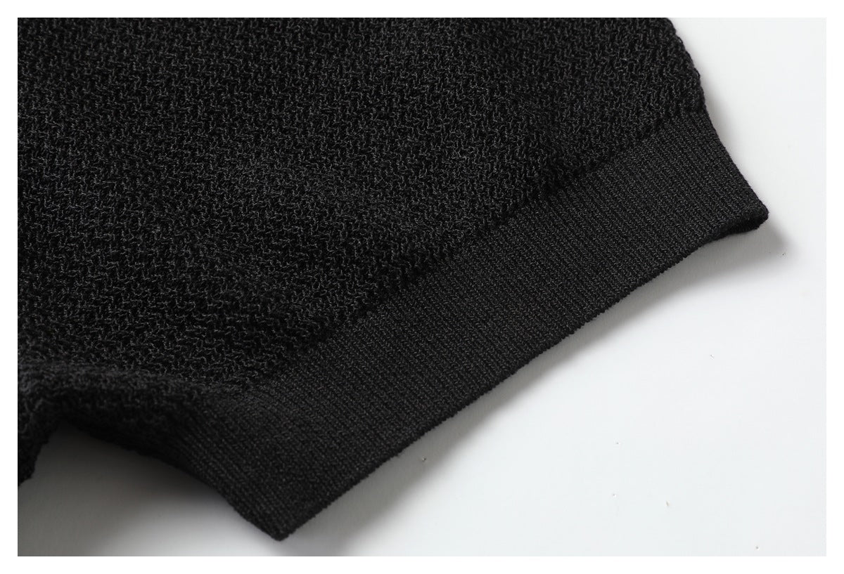 Close-up of the black polo's textured knit and ribbed sleeve cuff.
