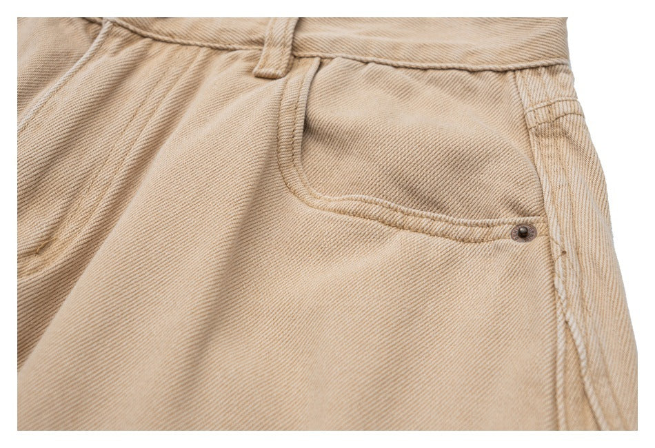 Close-up of beige twill trousers showing a curved front pocket, waistband and belt loop.