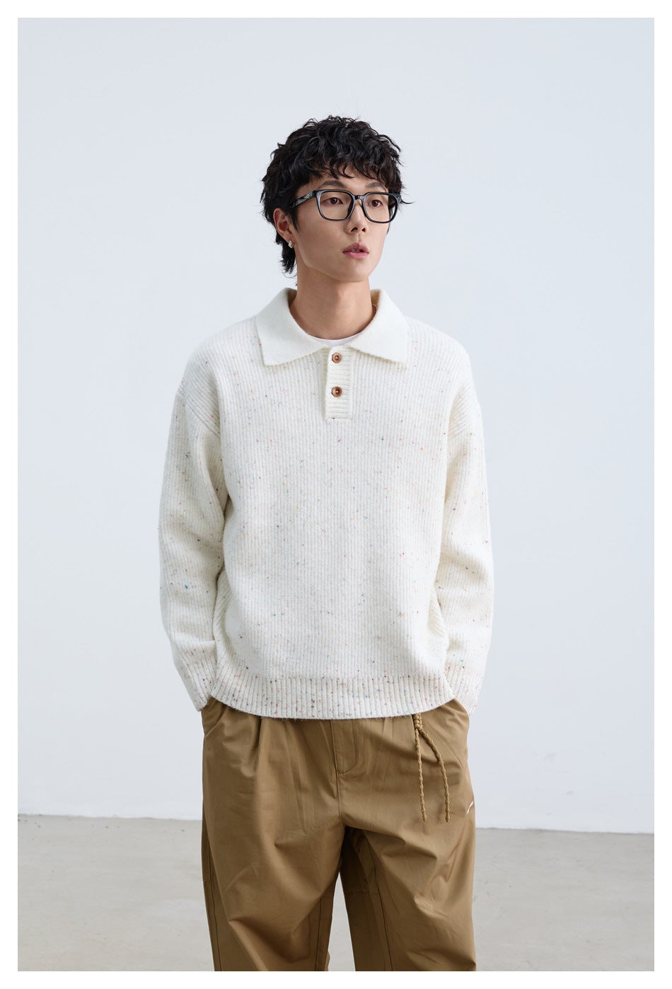 Front view of a model wearing an ivory flecked knit polo sweater with a white collar and brown buttons.