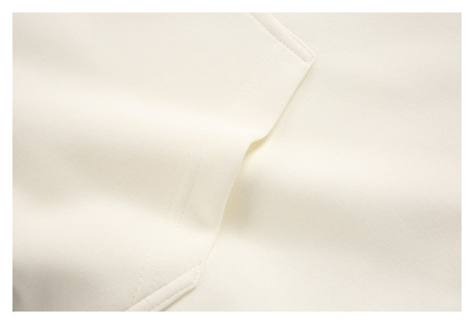 Close-up of an ivory garment panel with a curved seam and stitched edge.