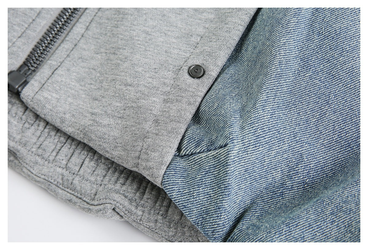 Close-up of a black zipper and snap on a gray knit panel beside blue denim fabric.