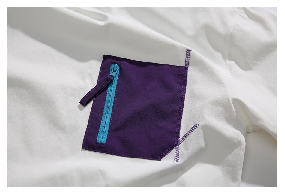 Close-up of the deep purple chest pocket and vertical bright blue zipper on the white shirt.