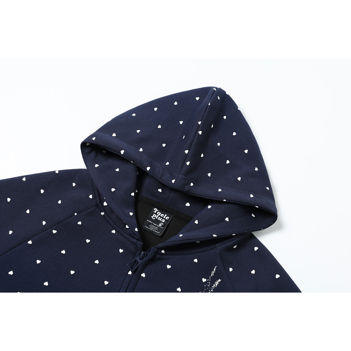 Close-up of a navy hoodie hood and shoulder with small white hearts, a zipper, and a black neck label.