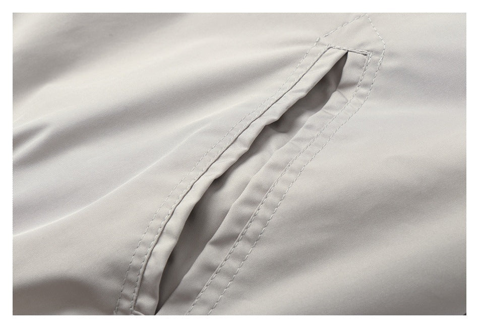Close-up of a slanted welt pocket opening on a light gray jacket.
