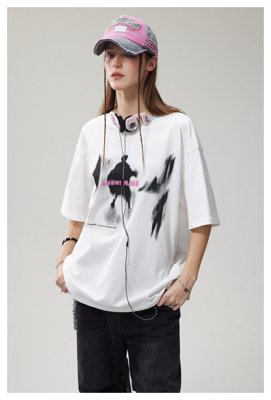 Closer view of a model wearing a white oversized T-shirt with abstract black brush-style graphics and pink lettering.