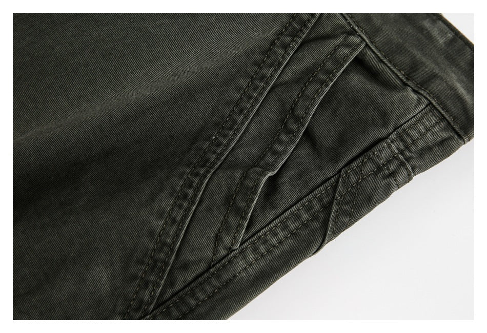 Close-up of charcoal trouser fabric and layered stitched seams near a pocket.