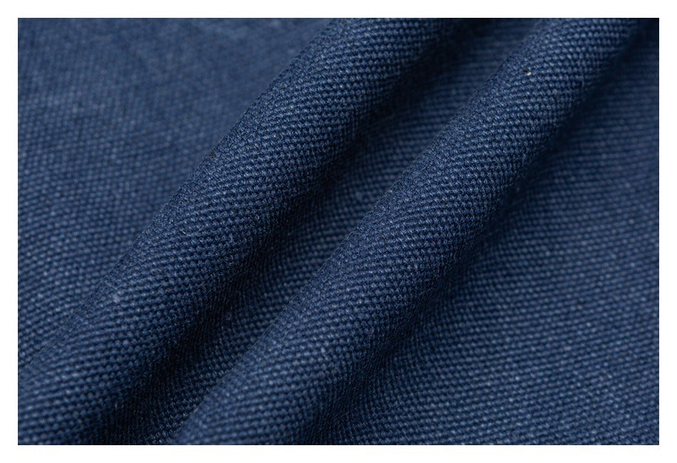 Macro view of dark blue woven fabric draped into folds, showing its textured weave.