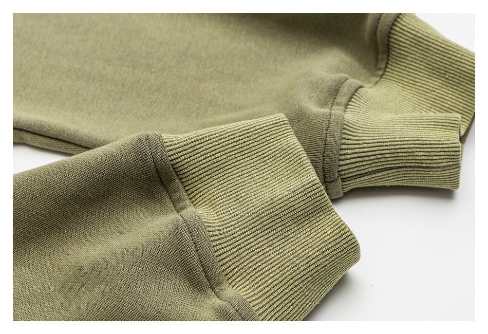 Close-up of olive green sweatshirt sleeves with wide ribbed cuffs and visible stitching.