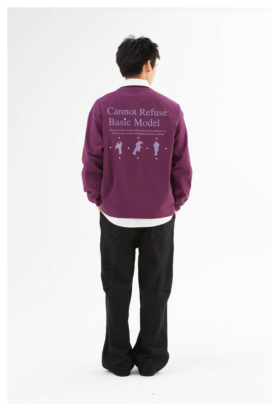 Model seen from behind wearing plum purple long-sleeve top with back text print over a white shirt and black pants