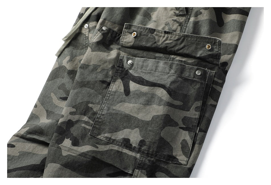 Close-up of gray and black camouflage trousers showing large cargo pockets with metal snaps.