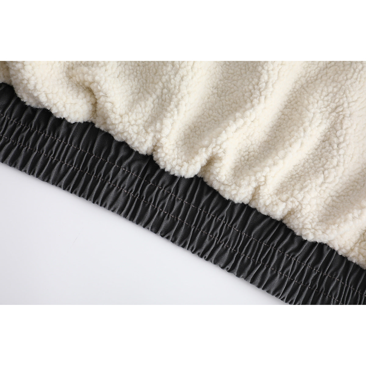 Close-up of cream textured lining meeting the charcoal jacket's gathered hem.