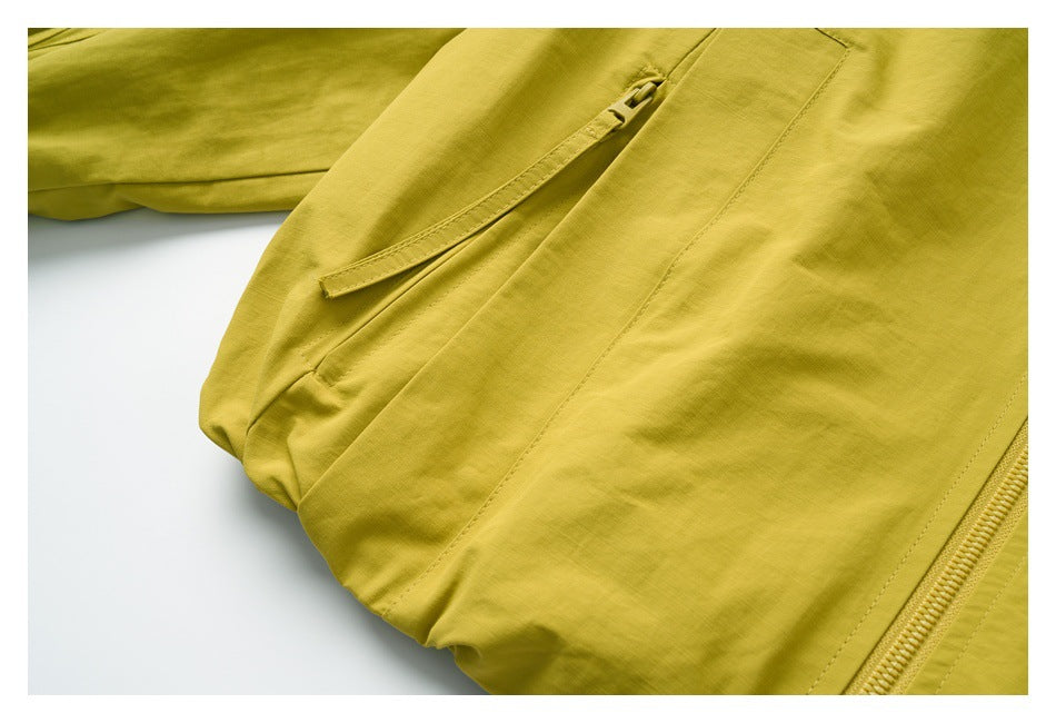 Close-up of a yellow-green garment showing a zip pocket with a fabric flap and part of the main zipper.