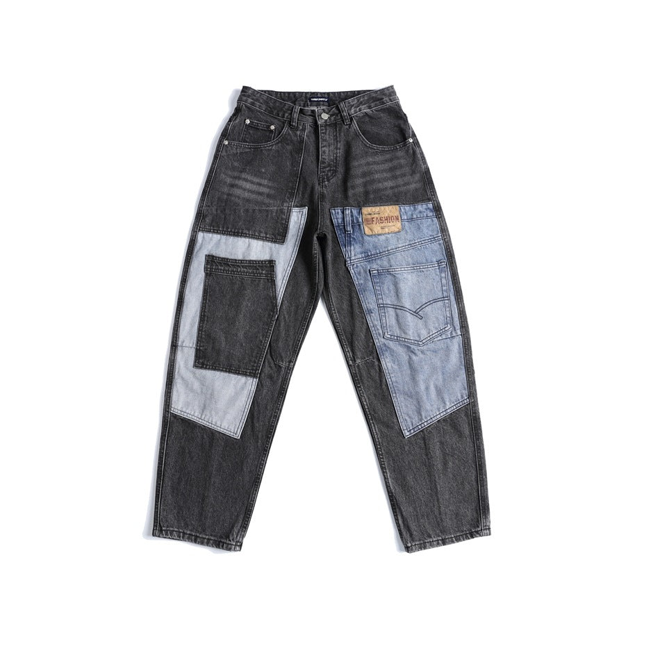 Black-gray washed jeans with light blue patchwork panels and a leather-look patch, flat lay front view