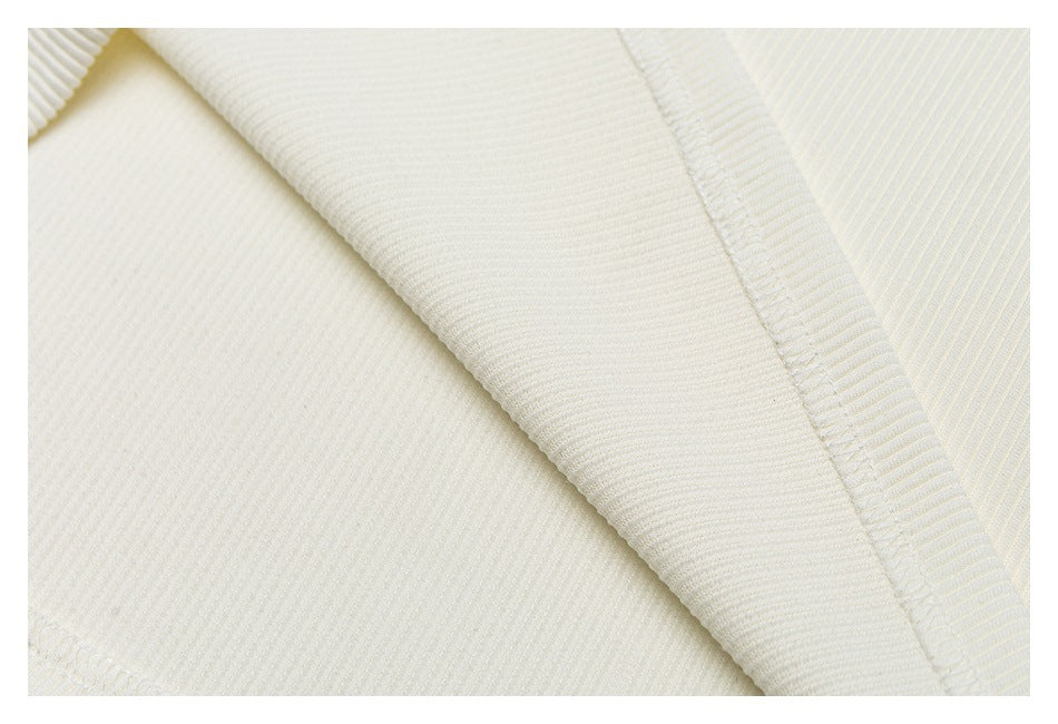 Close-up of ivory ribbed knit fabric with a diagonal folded edge and visible seam stitching.