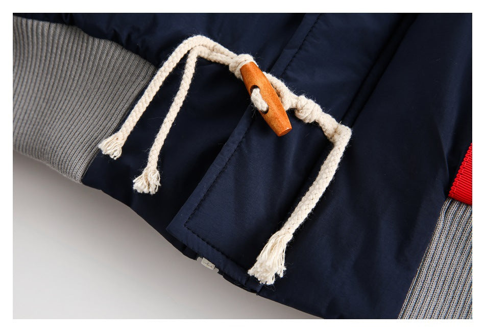 Close-up of a navy jacket with cream rope drawstrings, a wooden toggle and gray ribbed trim.
