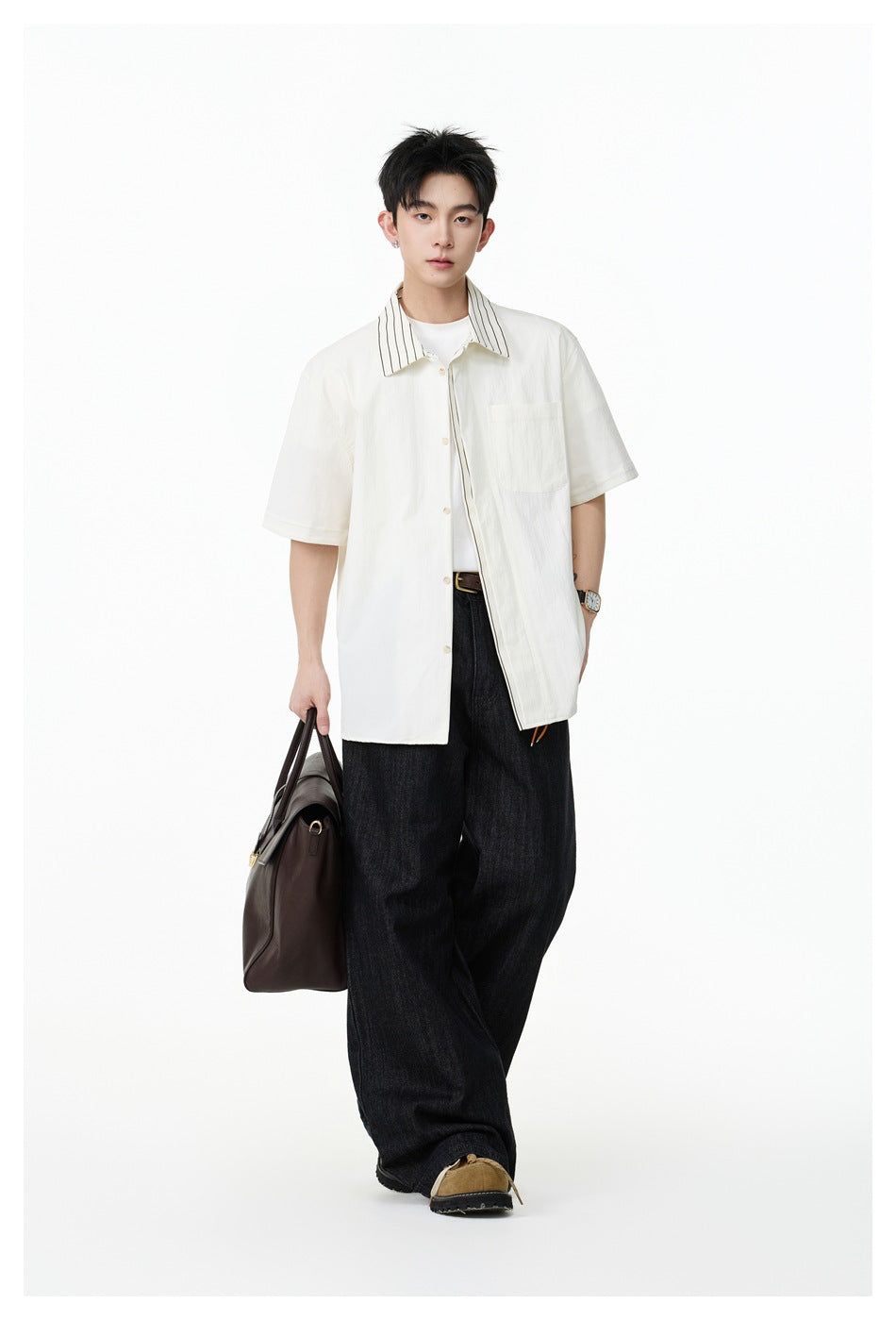 Model wearing an ivory short-sleeve button-up shirt with a striped collar and dark trousers.