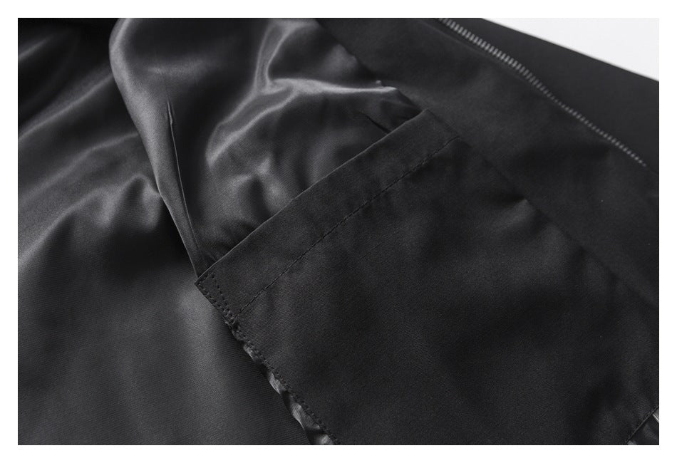 Interior view of a black garment showing smooth lining and a stitched pocket beside the zipper.