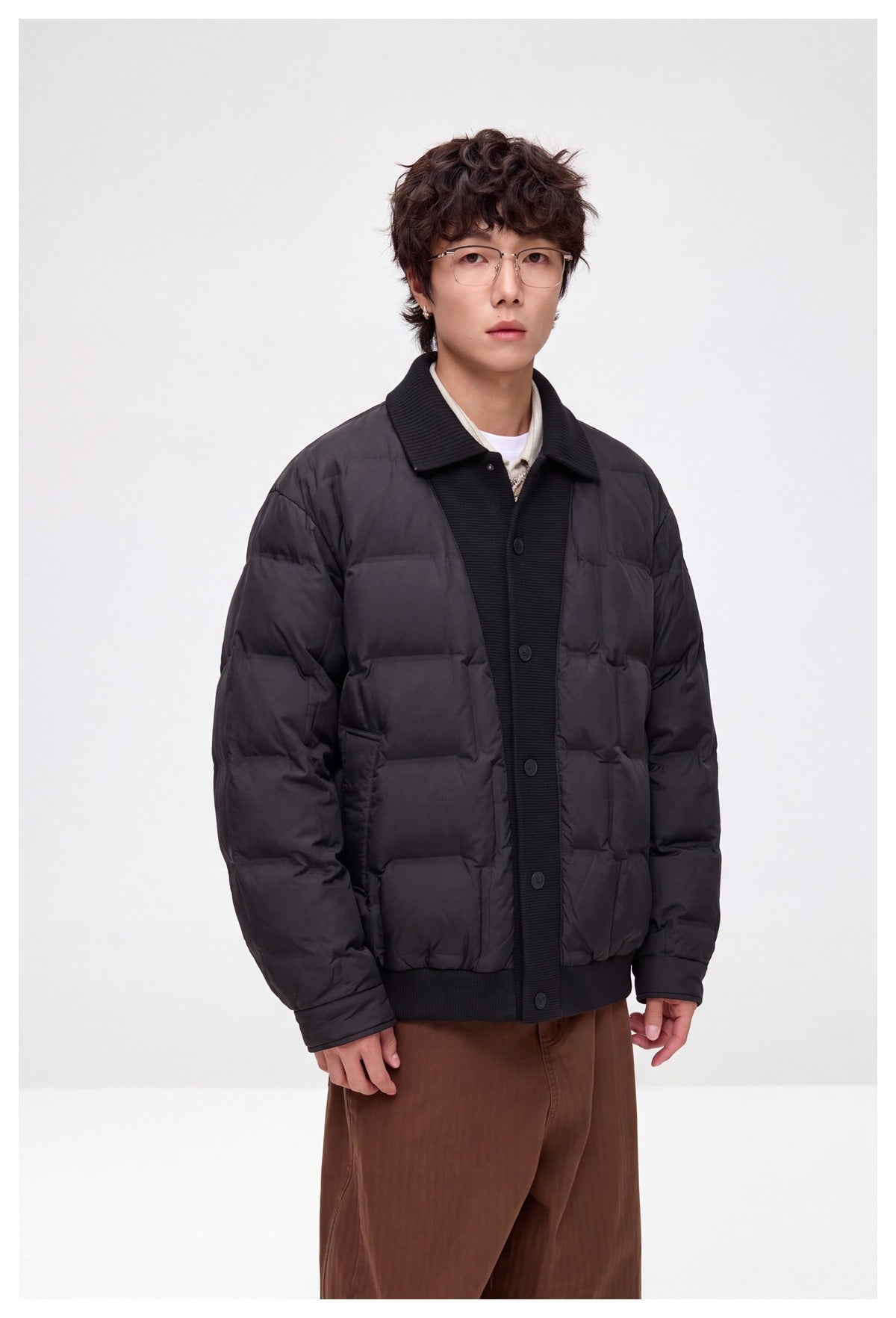 Model wearing a dark quilted button-front jacket with a ribbed collar and hem, shown from the front at a slight angle.