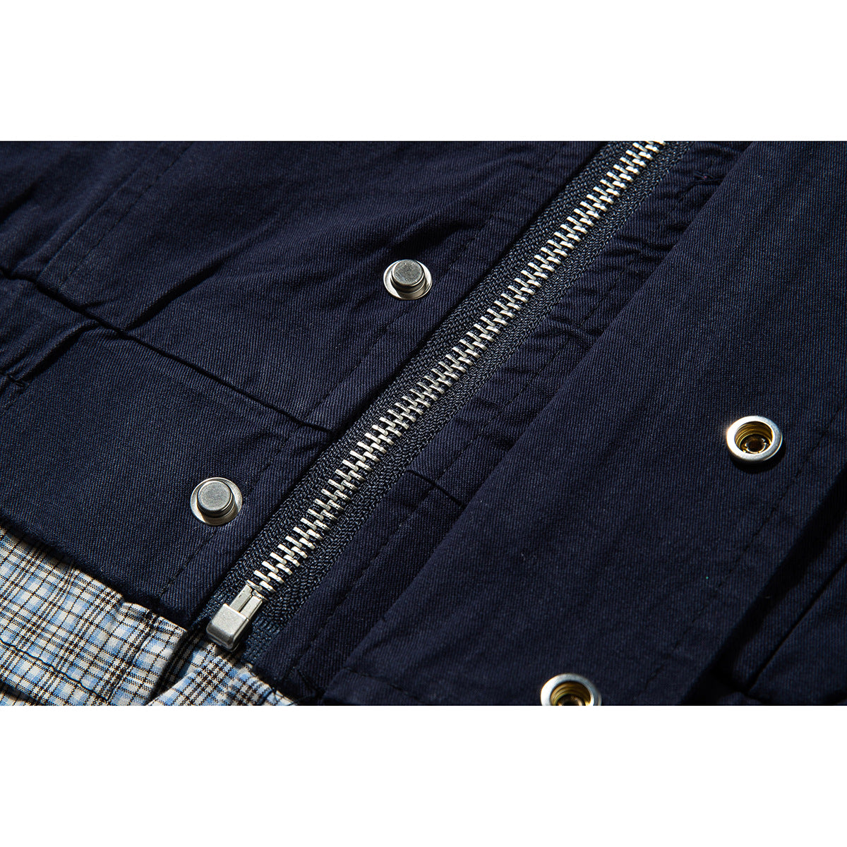 Close-up of a navy jacket's metal zipper, snap fasteners, and plaid lining.
