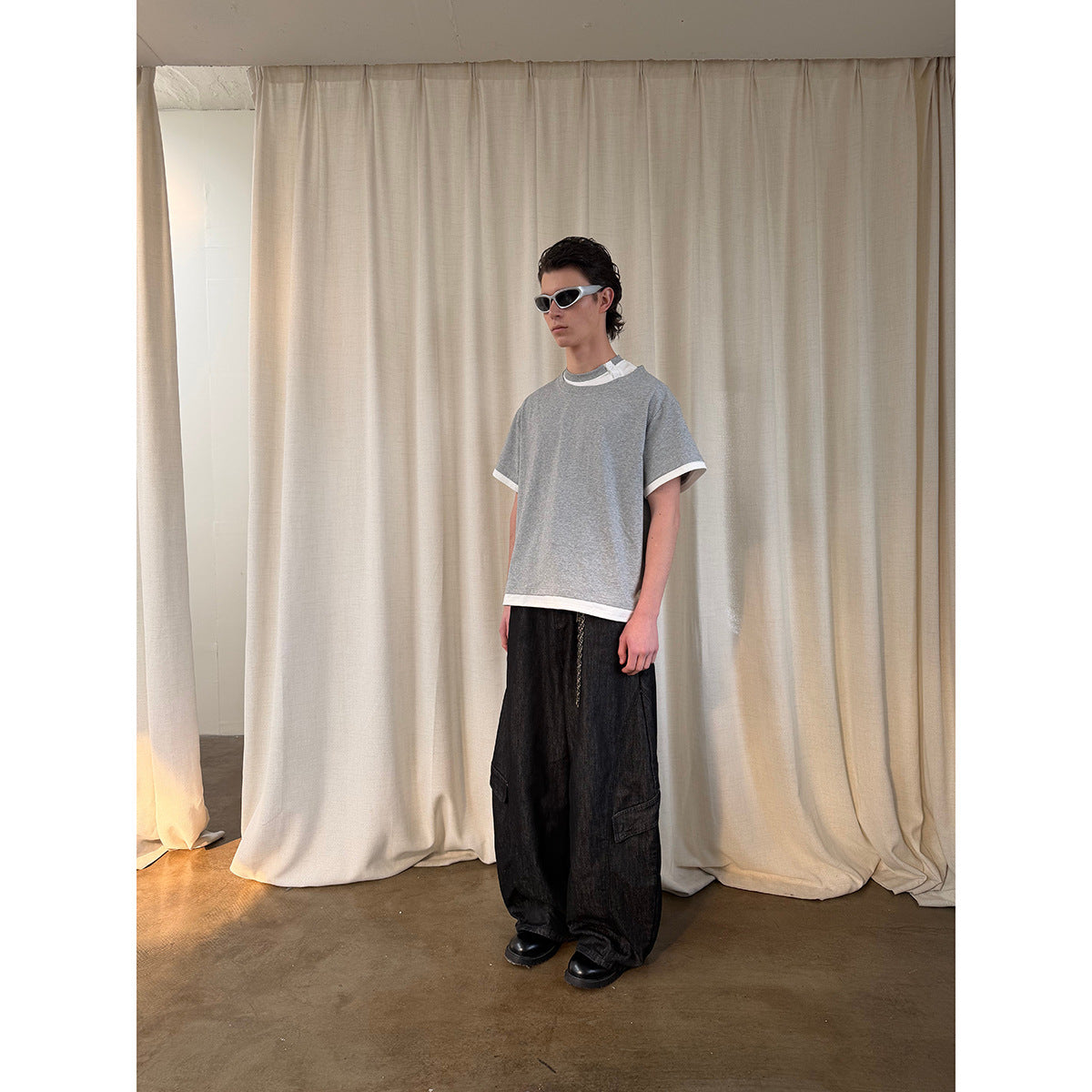 Three-quarter view of a model in an oversized gray T-shirt with white sleeve and hem trim.