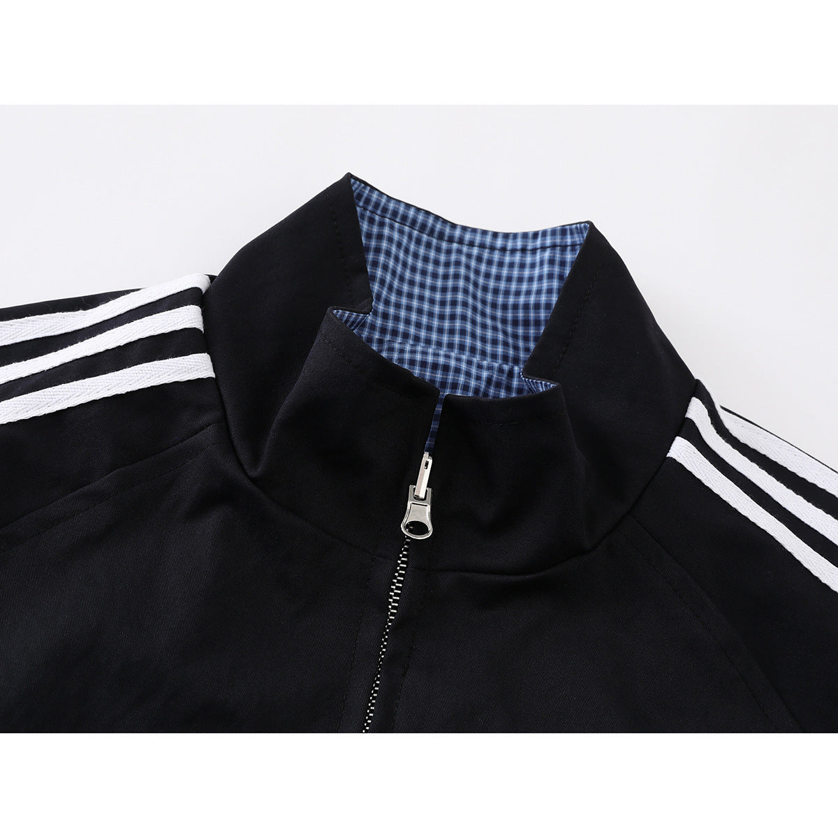 Close-up of a black jacket with a blue check lining inside the stand collar and a silver front zipper.