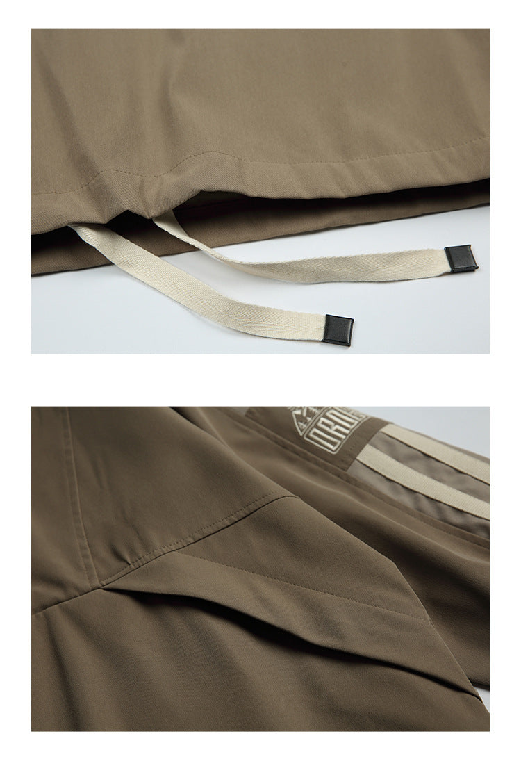 Taupe jacket hem with two long cream drawcords and black end tabs; lower panel shows a curved seam detail.