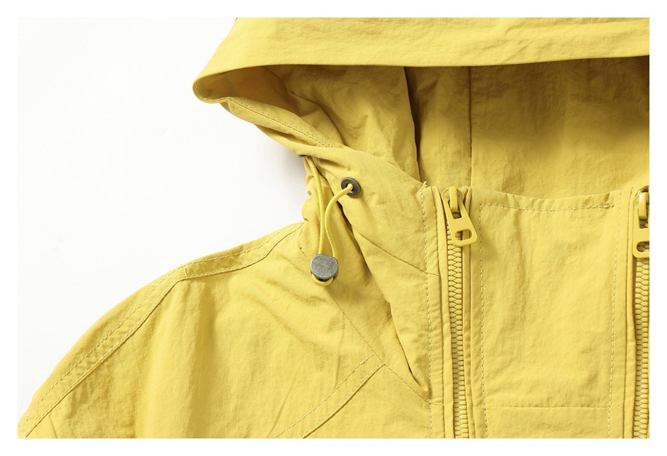 Close-up of the yellow jacket's hood drawcord, metal eyelet, and paired front zippers.